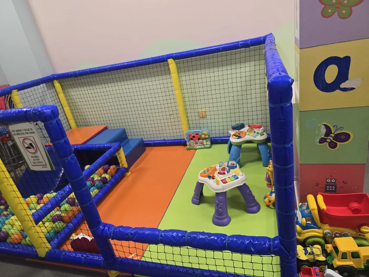 Zona vallada de bebés con piscina de bolas y mesas de actividades